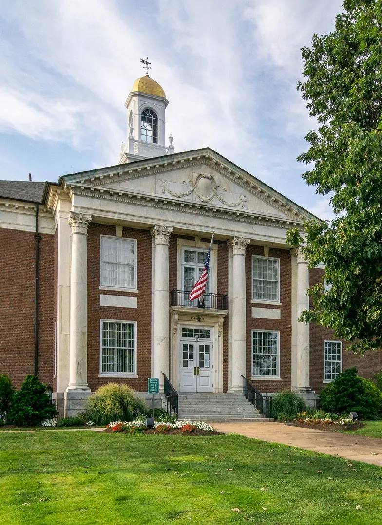 Manchester Town Hall, a brick Colonial Revival building with white marble columns, a gold-domed cupola and a US flag above the entrance.